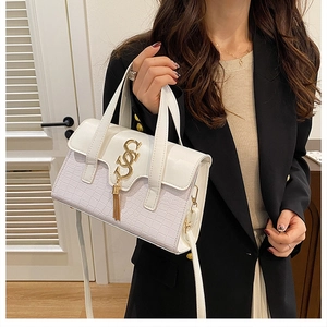 Details der weißen Lederhandtasche mit Krokostruktur, Goldfransen und Kettenschloss