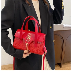 Red crocodile pattern tote bag with gold lettering and tassel on a stylish model