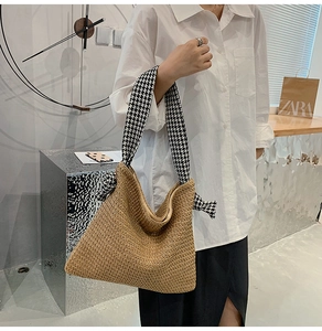 Detail of woven straw tote bag featuring decorative houndstooth fabric wrap on handle
