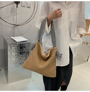 Detail view of woven straw tote bag featuring chic houndstooth fabric knot shoulder strap