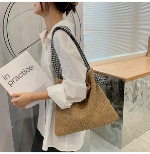 Detail of hand-woven straw tote bag with black and white houndstooth fabric shoulder strap