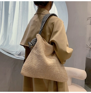 Detail of hand-woven straw tote bag with black and white houndstooth shoulder strap