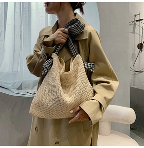 Close-up of straw tote bag featuring houndscart scarf handle on model in trench coat