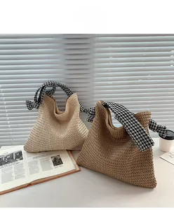 Close-up of woven straw texture and houndstooth fabric handle on minimalist summer tote