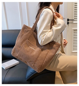 Detail of a brown corduroy tote bag with Free Gold embroidery shown on a stylish model