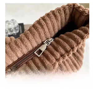Detail shot of smooth silver metal zipper on textured brown corduroy tote bag surface