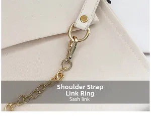 Detail of the golden metal chain link and spring hook on the cream canvas shoulder bag