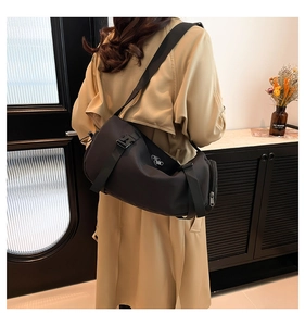 Detail of the black cylinder crossbody bag with wide adjustable strap and quick-release buckle