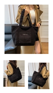 Detail of black corduroy tote bag showing ribbed texture and embroidered front pocket