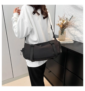Detail view of the black cylindrical messenger bag showing adjustable buckles and nylon fabric