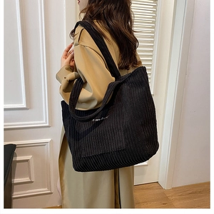 Close-up of black corduroy tote bag featuring white Free-color embroidery on a shoulder strap