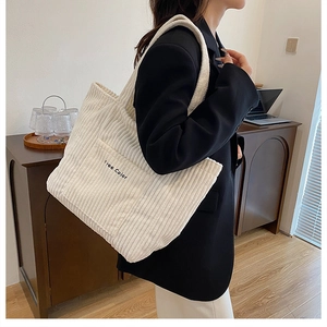 Detailed texture of white corduroy tote bag with black Free Color embroidery