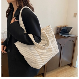 Detail of white corduroy tote bag featuring Color embroidery shown in casual setting