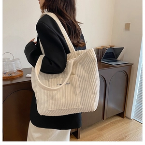 Close-up of beige corduroy tote bag featuring Free Color embroidery and ribbed texture