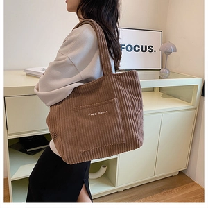 Detail of a brown corduroy tote bag with side pocket and Free Color embroidery detail