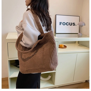 Detail view of large brown corduroy tote bag featuring a front pocket and soft texture