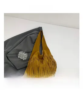 Detail view of mustard yellow faux suede shoulder bag with long bohemian tassels