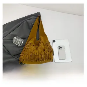 Flat lay of ginger suede tassel shoulder bag with fashion accessories and tablet