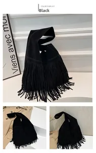Detailed view of long tassels on black faux suede bucket bag with wide handle
