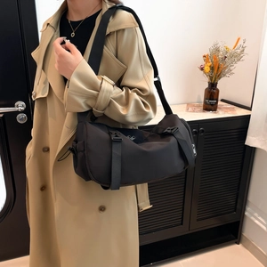 Minimalist black cylinder crossbody bag for women with adjustable strap and large capacity