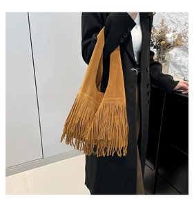 Detail of bohemian camel suede shoulder bag featuring long fringe and a spacious design
