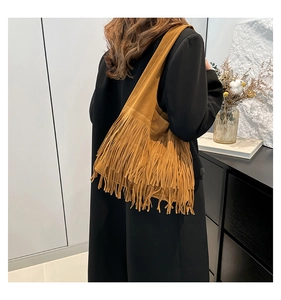 Detail of brown faux suede tote bag with long tassel fringe held by a model