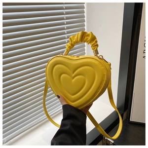 Détail du sac à main jaune en forme de cœur avec couches matelassées et poignée plissée