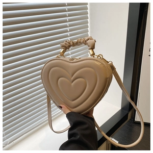 Détail d'un sac à main beige en forme de cœur avec gaufrage triple couche et anse froncée