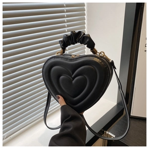 Détail du sac à main noir en forme de cœur avec matelassage et poignée plissée