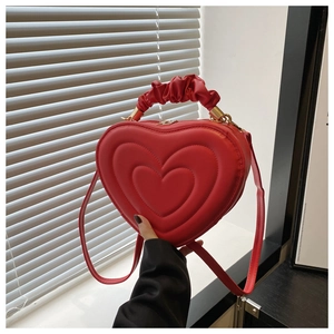 Détail du sac à main rouge en forme de cœur avec poignée plissée et relief texturé