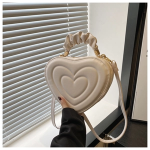 Détail du sac coeur en cuir crème avec design triple matelassé et poignée froncée