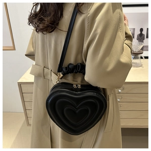 Detail of black heart-shaped PU leather bag with pleated handle and golden zippers