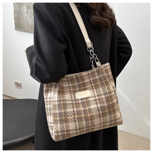 Détail du sac cabas à carreaux avec bandoulière chaîne cuir et étiquette sur tweed
