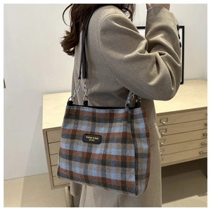 Detail of wool plaid tote bag with silver chain straps and branded fashion label