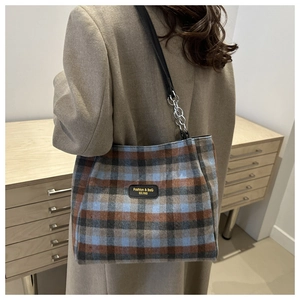 Détail du sac cabas vintage à carreaux avec bandoulière chaîne et écusson en cuir