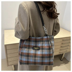 Détail du sac cabas à carreaux avec écusson en cuir et accents de chaîne argentée