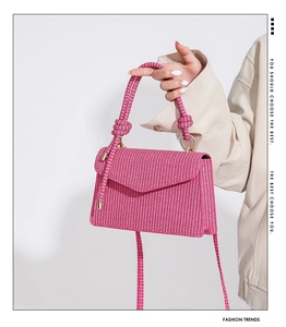 Detailed macro view of pink woven texture and knotted rope handle on the stylish handbag