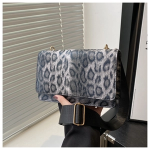 Detail der grau-leoparden Tasche mit goldenen Beschlägen und breitem schwarzen Gurt