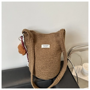 Detailed view of brown fleece bucket bag with teddy bear charm on leather seat