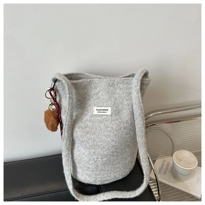 Detail of grey lamb wool bucket bag with plush pom-pom charm and ZYJ design label