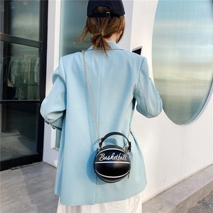 Fashionable black basketball shaped crossbody bag with chain strap on a model