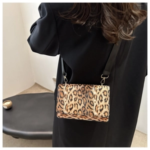 Detailaufnahme der Umhängetasche mit Leopardenmuster, breitem Gurt und Goldbeschlägen
