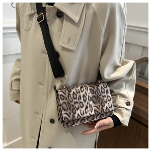 Detail der Leoparden-Umhängetasche mit schwarzem Gurt auf beigem Trenchcoat