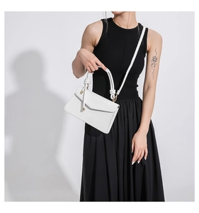 Detailed view of white crossbody bag with woven texture and decorative knotted handle