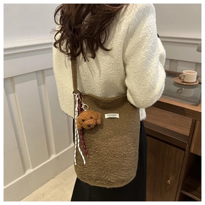 Close-up of brown fuzzy fleece bucket bag with a cute dog plush keychain and woven rope detail