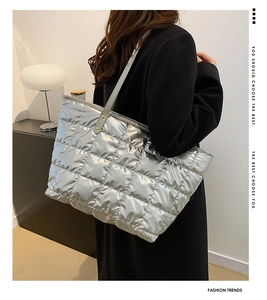 Detail showing the shiny silver quilted tote bag with a metallic finish on a shoulder strap
