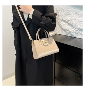 Detail of elegant beige crossbody bag with floral gold buckle and faux crocodile texture