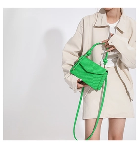 Close-up of bright green woven handbag with knot handle and texture on a model