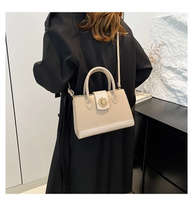 Detail of a beige leather handbag with crocodile pattern base and floral metal buckle