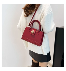 Detail of red crocodile texture handbag featuring a golden flower-shaped metal buckle